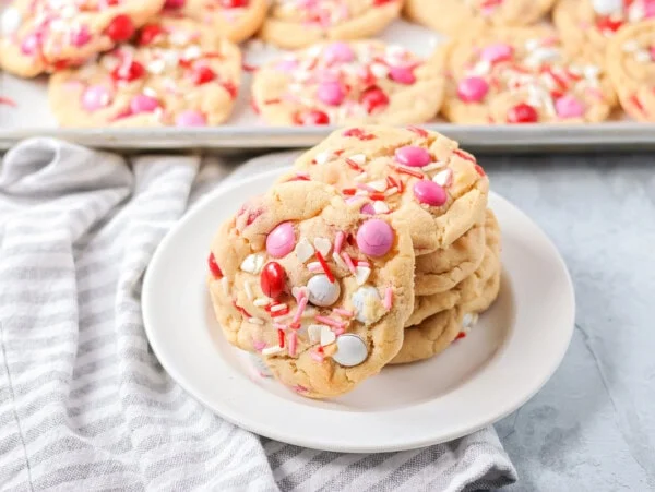 A stack of Valentines Day cookies on a white plate.