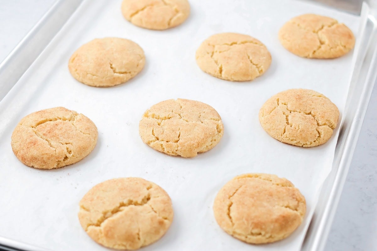 Family favorite brown butter snickerdoodle recipe is easy to make with a soft center, classic tang, and cozy flavor. Baked cookies on a cookie sheet.