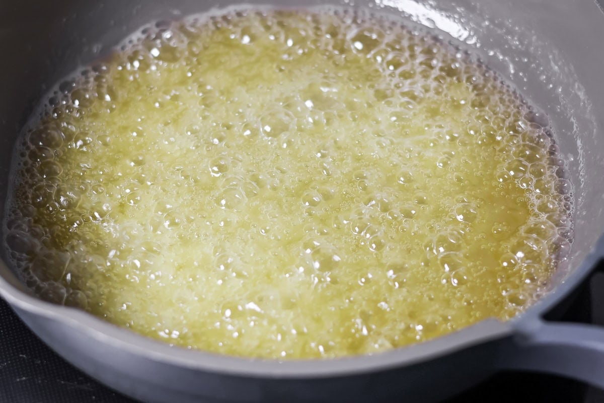 Family favorite brown butter snickerdoodle recipe is easy to make with a soft center, classic tang, and cozy flavor. Melted butter heating in a pan.