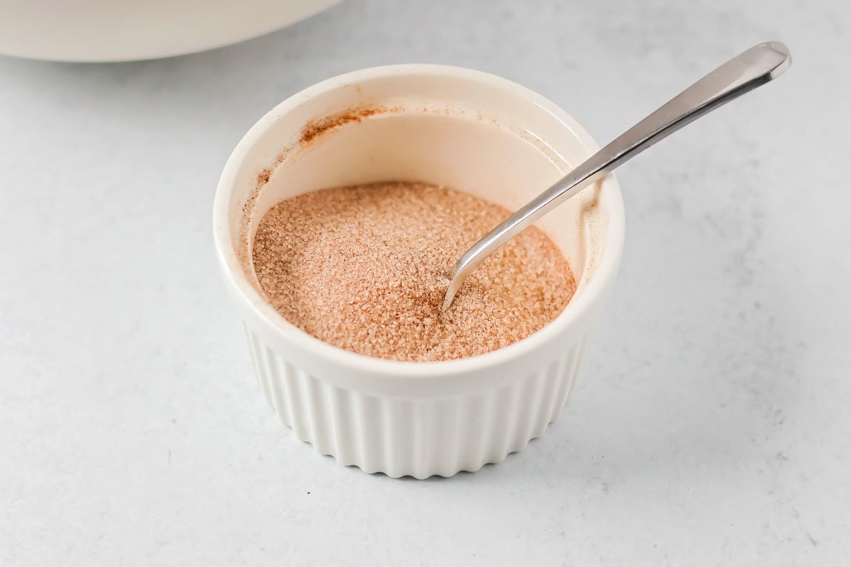 Family favorite brown butter snickerdoodle recipe is easy to make with a soft center, classic tang, and cozy flavor. cinnamon sugar mixture in a small bowl.