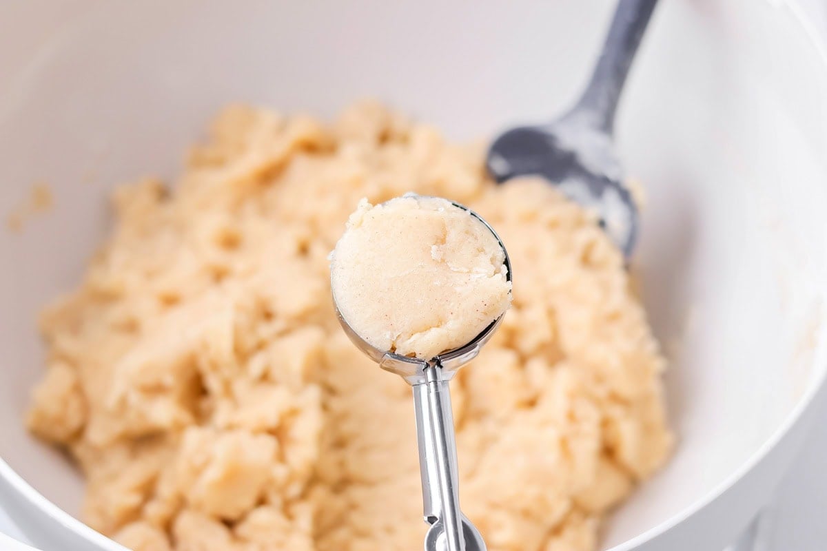 Family favorite brown butter snickerdoodle recipe is easy to make with a soft center, classic tang, and cozy flavor. Scooping cookie dough.