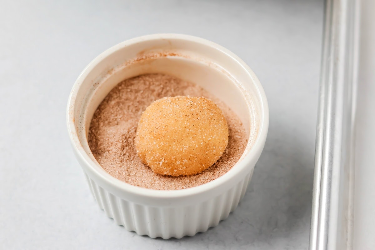Family favorite brown butter snickerdoodle recipe is easy to make with a soft center, classic tang, and cozy flavor. Rolling cookie dough ball in cinnamon suagr.