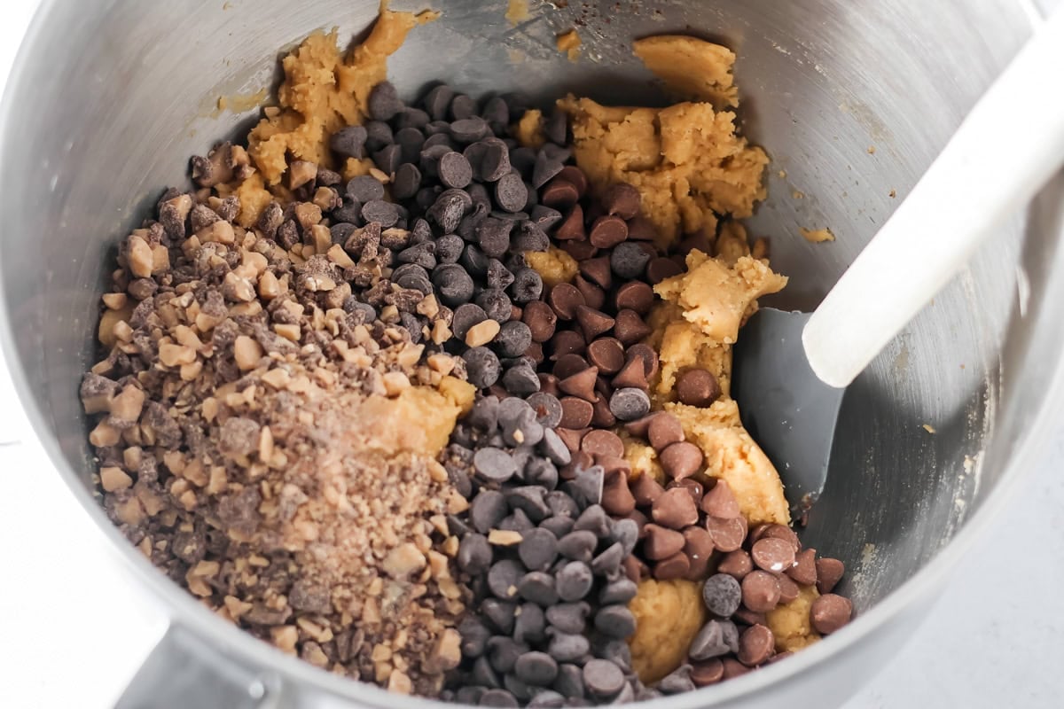 Browned butter toffee chocolate chip cookies with chewy centers and melty chips is an easy bakery-style cookie the whole family loves. Toffee and chocolate chips on top of cookies dough in a mixing bowl.
