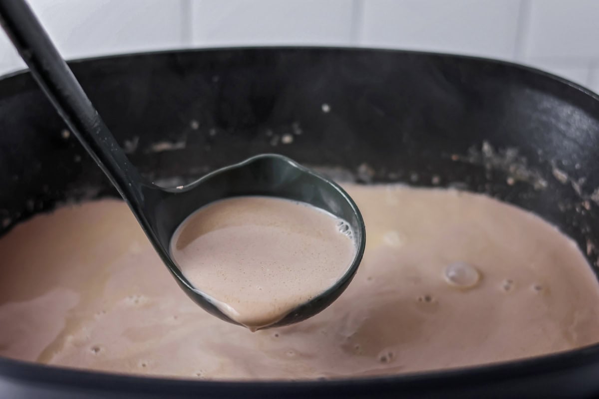 Slow cooker hot cocoa being ladled out of slow cooker.