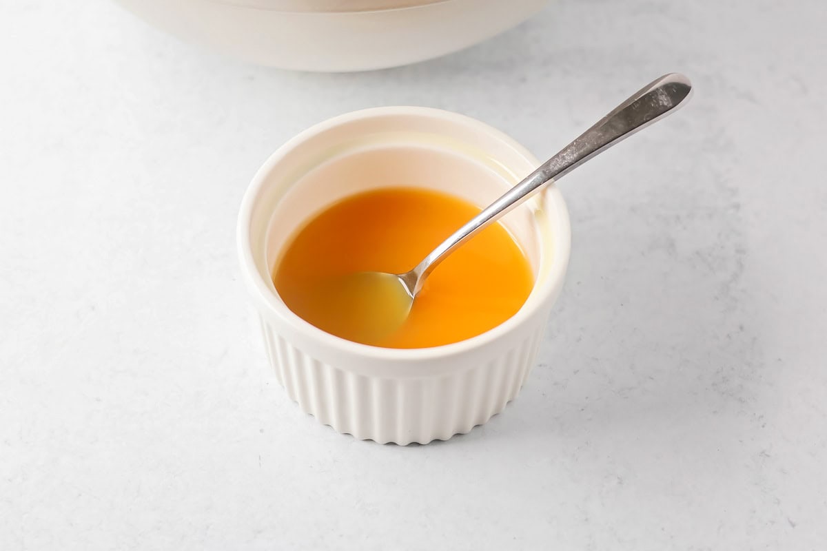 Bright and refreshing, this winter fruit salad blends clementines, kiwi, apples, pear, and pomegranate with a light citrus honey dressing. Homemade citrus honey dressing in a white ramekin.