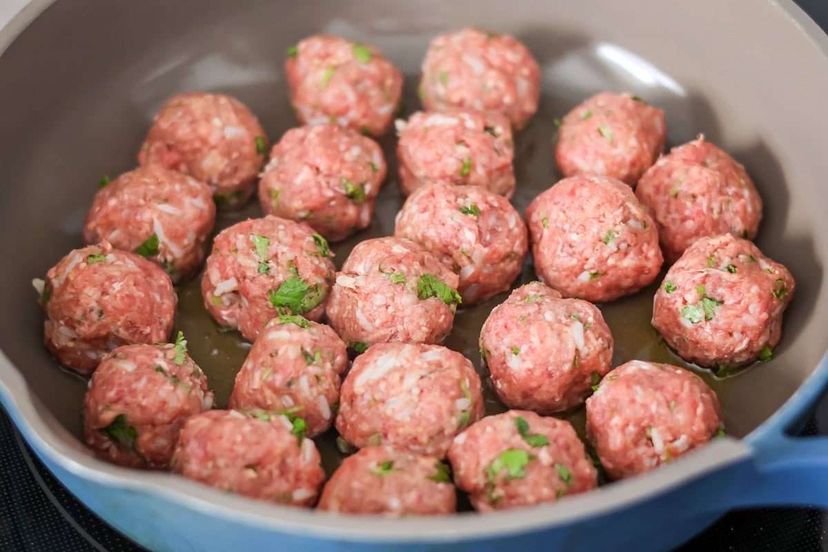 Meatballs being browned in skillet.