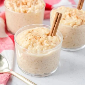 Homemade arroz con leche recipe in glass cups with cinnamon sticks.