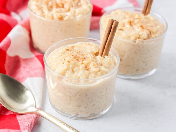 Homemade arroz con leche recipe in glass cups with cinnamon sticks.