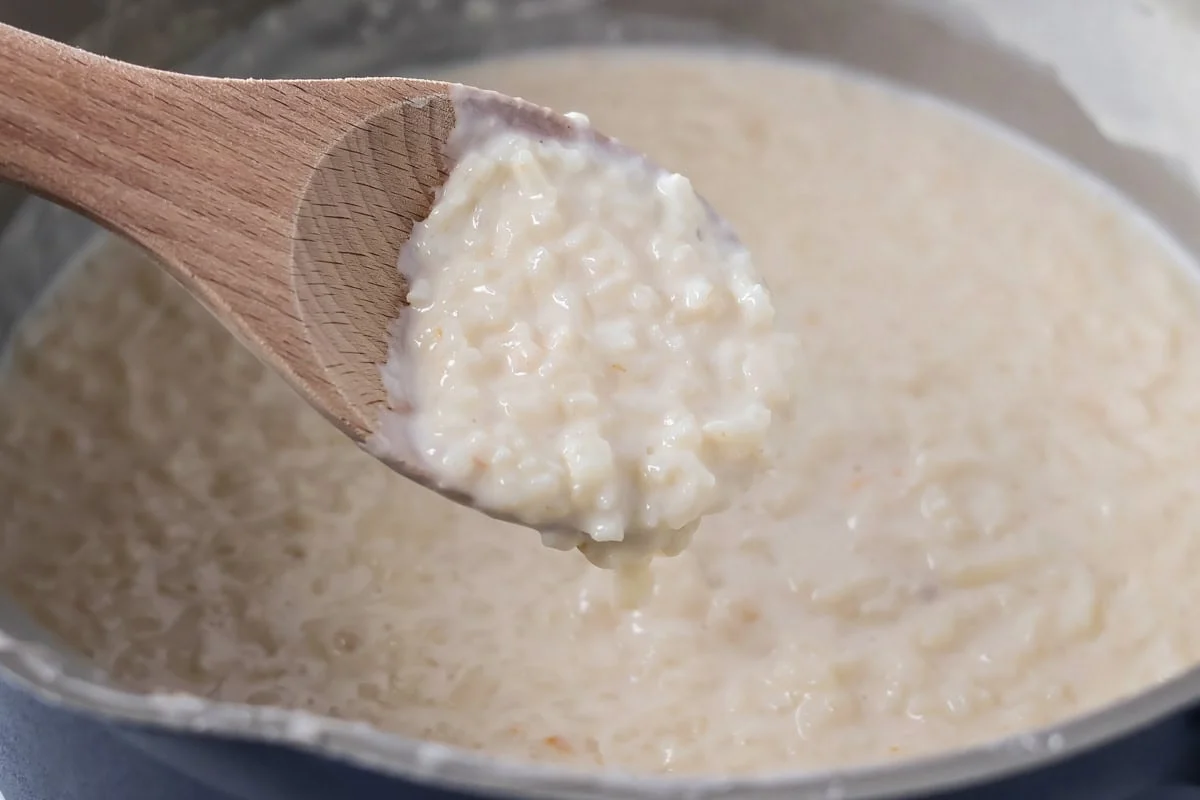 Spooning out homemade arroz con leche from pan. 