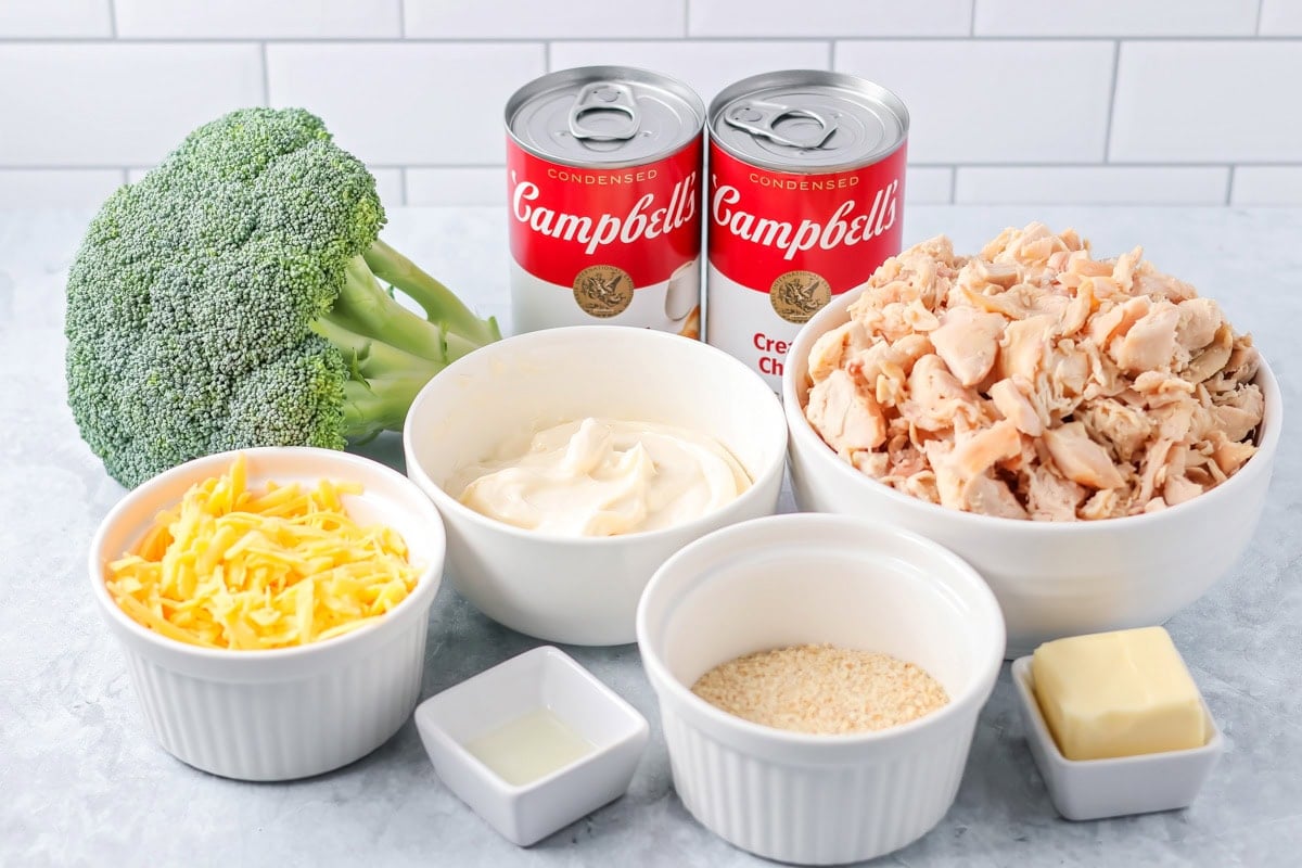 Chicken and broccoli casserole is loaded with veggies and cheesy flavor - a simple family favorite for generations! Broccoli cheese casserole ingredients on white countertop.