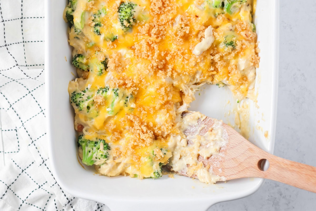 Chicken and broccoli casserole is loaded with veggies and cheesy flavor - a simple family favorite for generations! Chicken and broccoli casserole being scooped out of baking dish.