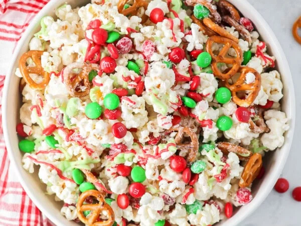 Homemade Christmas popcorn mixed together in white bowl.
