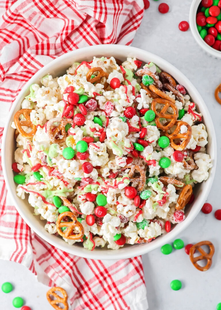 Homemade Christmas popcorn mixed together in white bowl.