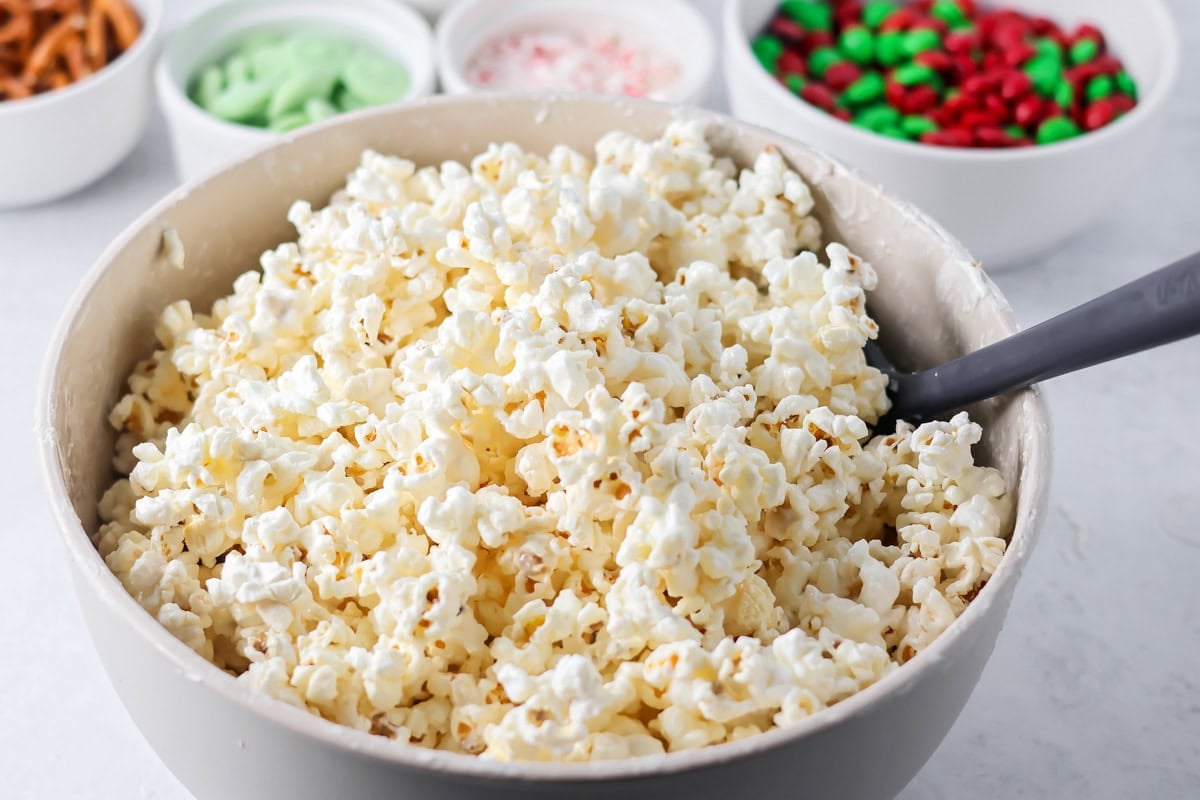Popcorn coated in melted white chocolate in mixing bowl.