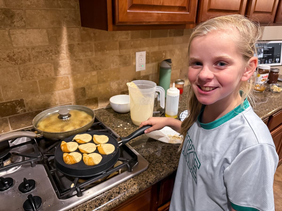 A girl making Aebleskivers with friends.