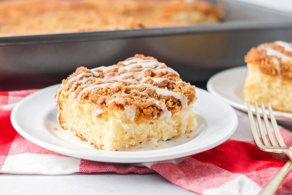 Cream cheese coffee cake slice on white plate with fork.