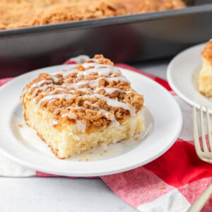 Slice of cream cheese coffee cake on white plate.