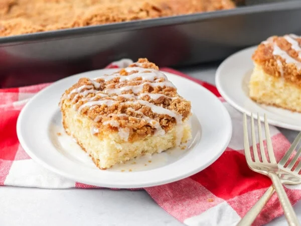 Slice of cream cheese coffee cake on white plate.