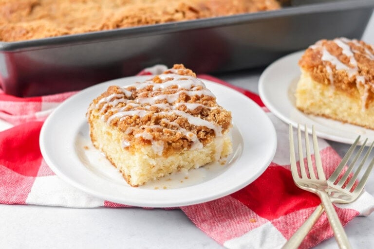 Slice of cream cheese coffee cake on white plate.