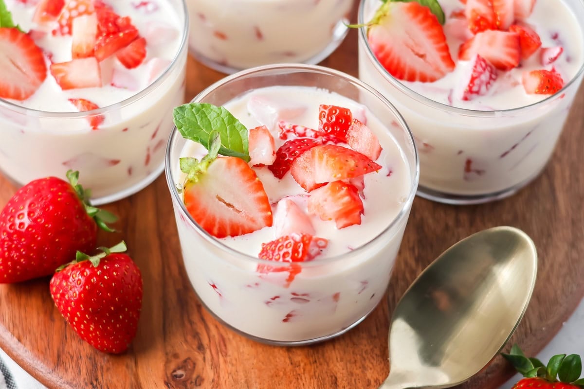 Fresas con Crema mixes strawberries with a silky vanilla cream. This 10-minute, no-bake dessert chills into spoonable perfection. A galss serving dish with frescas con crema.