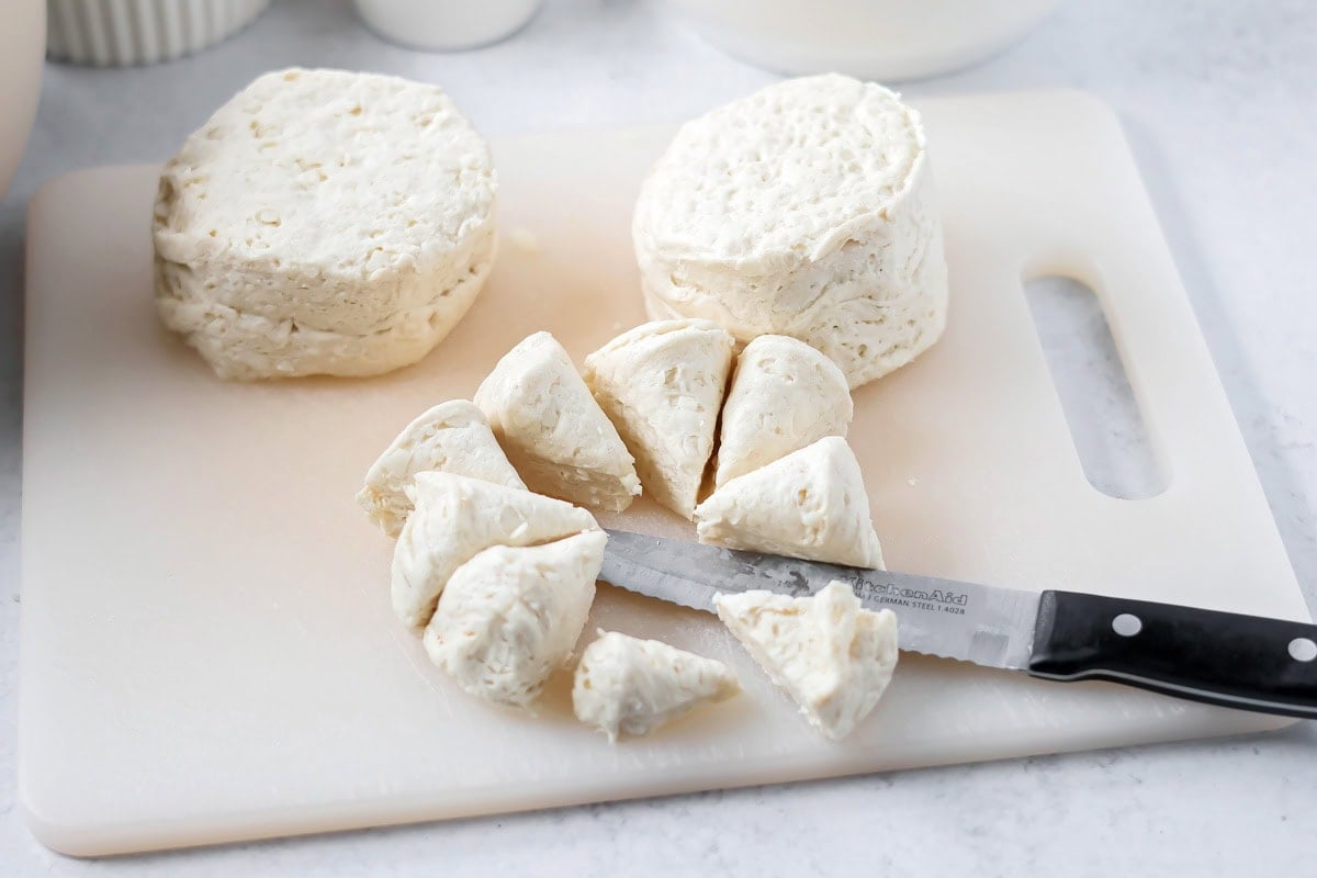 Biscuits being cut into pieces on cutting board.