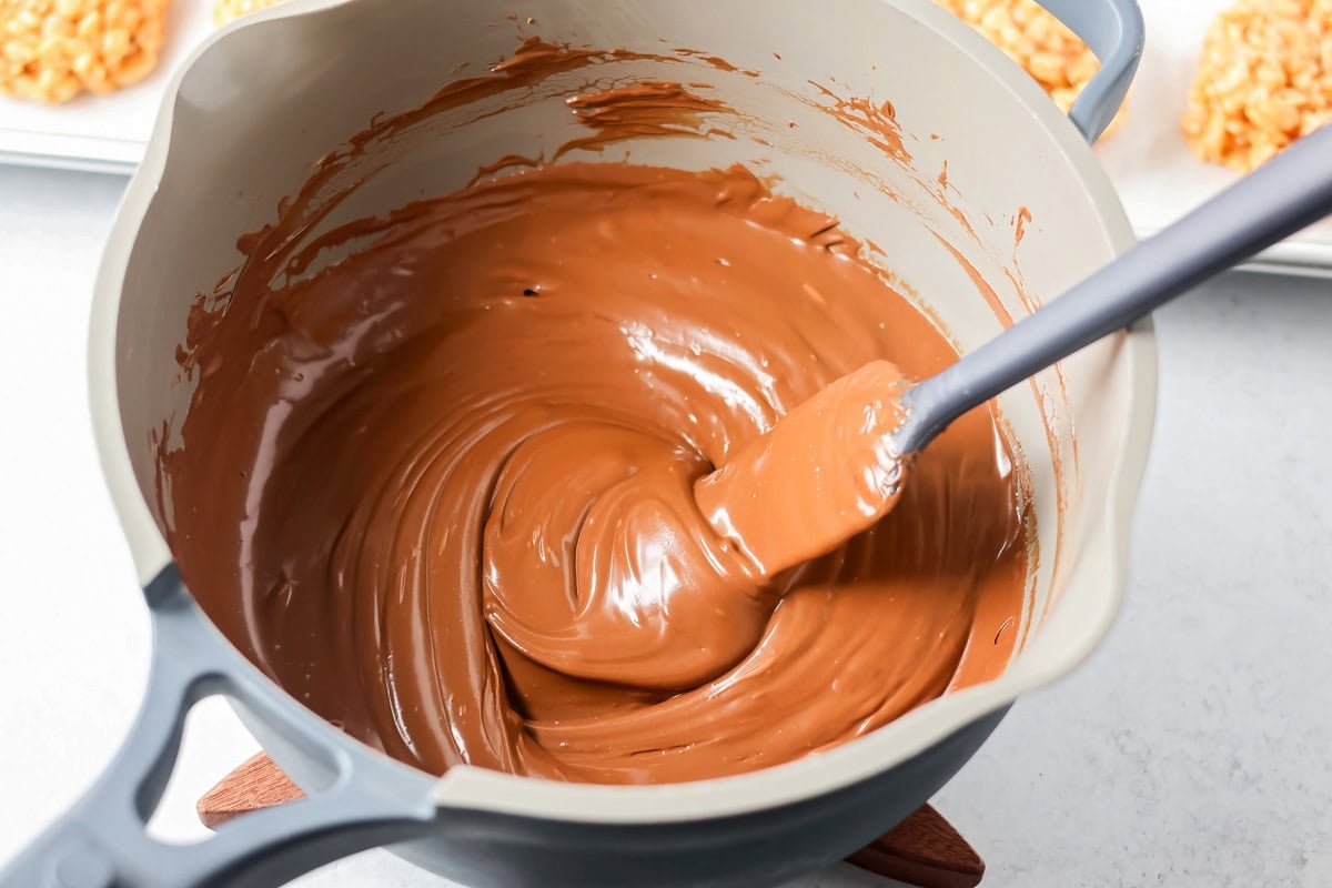 These scotcharoo cookies with crispy cereal, peanut butter, and a chocolate butterscotch topping are perfect for parties and evenings at home. Melted chocolate and butterscotch chips in a sauce pot.