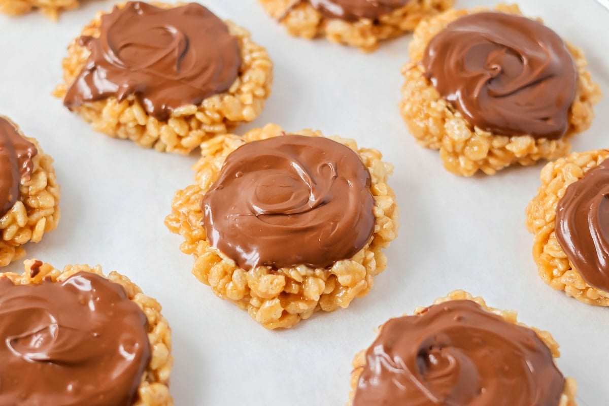 These scotcharoo cookies with crispy cereal, peanut butter, and a chocolate butterscotch topping are perfect for parties and evenings at home. Scotcheroo cookies lined on a baking pan.
