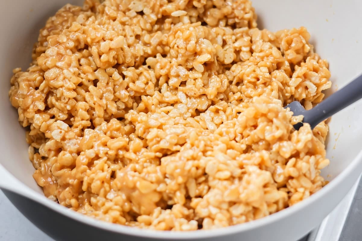 These scotcharoo cookies with crispy cereal, peanut butter, and a chocolate butterscotch topping are perfect for parties and evenings at home. Peanut butter coated rice krispies cereal in a bowl.