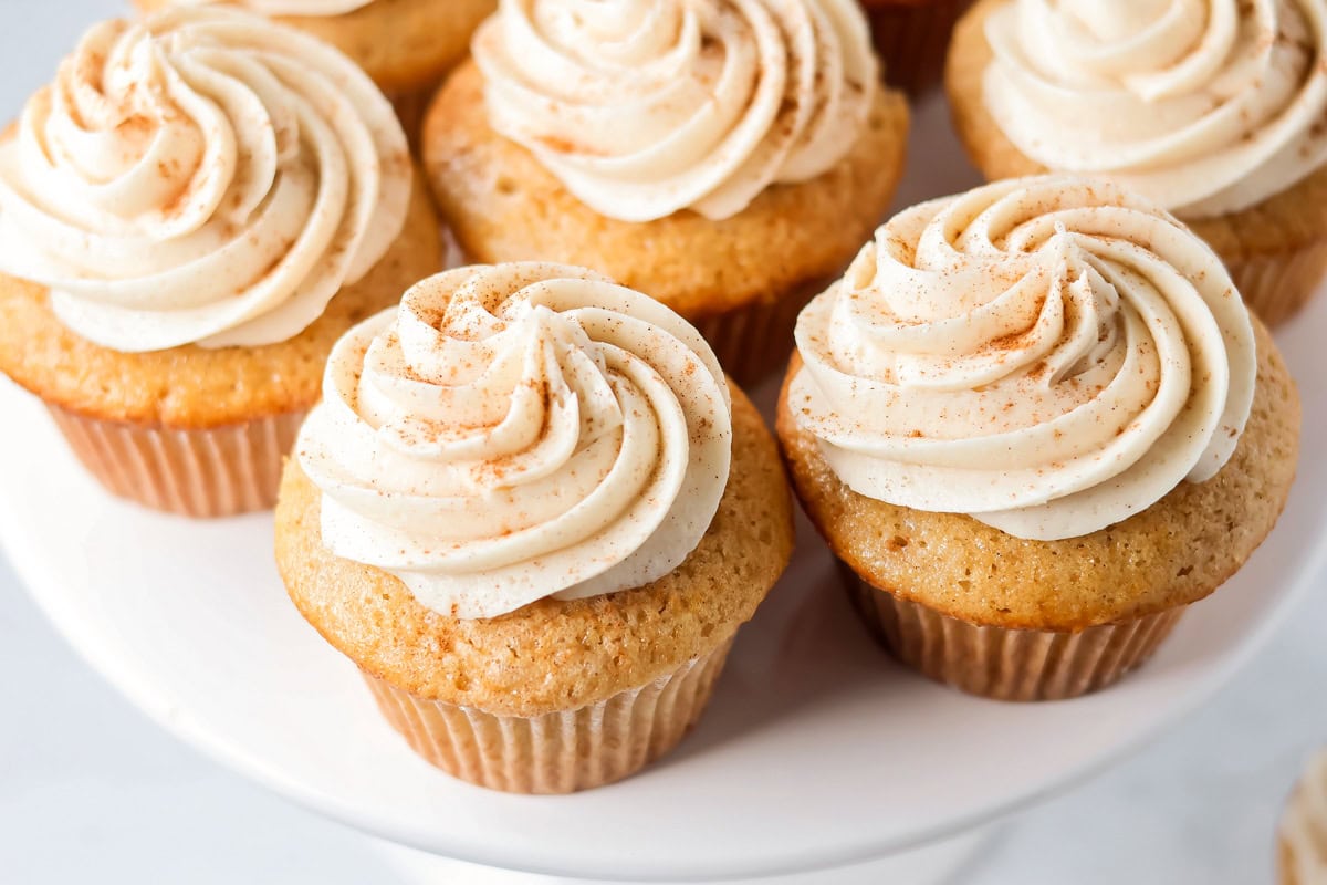 Soft cinnamon honey cupcakes with a crackly sugar top and creamy frosting, easy to make and perfect for parties or cozy weeknights. Sopapilla Cupcakes on a cake stand.