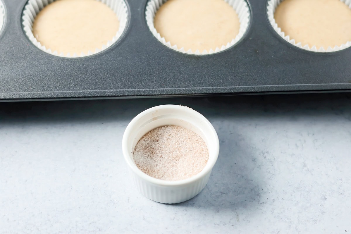 Soft cinnamon honey cupcakes with a crackly sugar top and creamy frosting, easy to make and perfect for parties or cozy weeknights. A small bowl of mixed cinnamon and sugar.