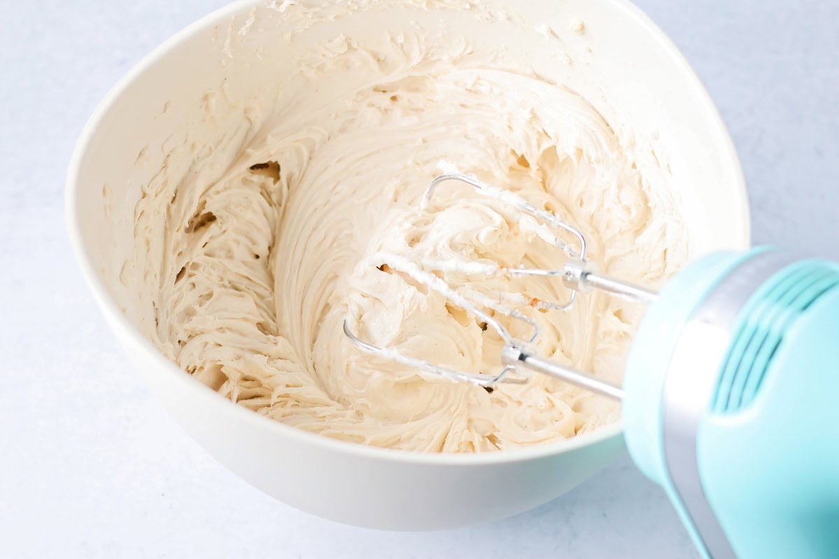 Soft cinnamon honey cupcakes with a crackly sugar top and creamy frosting, easy to make and perfect for parties or cozy weeknights. Frosting mixed in a mixing bowl.