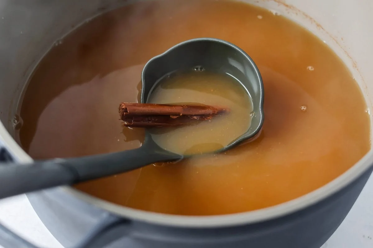 Homemade wassail recipe being scooped out of pan.