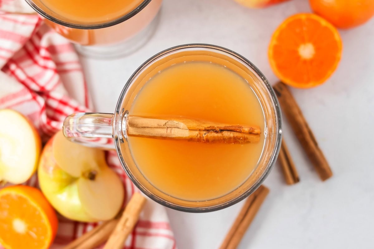 This wassail recipe is a sweet and spicy mulled cider full of citrus and cinnamon flavor. Make this cozy drink a holiday tradition! Wassail drink recipe poured into glass with cinnamon stick in it.