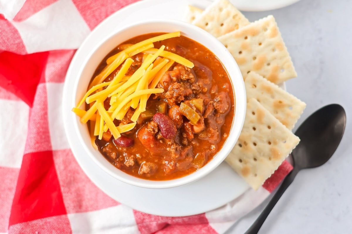 This copycat Wendy's chili recipe captures the bold spices and hearty comfort of the fast-food favorite, for a hearty bowl-full at home!! Wendy's chili recipe in bowl with crackers and spoon on the side.