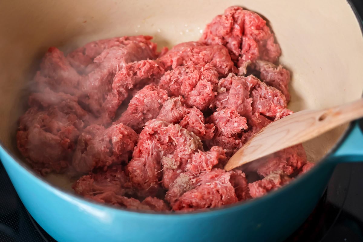 Cooking hamburger meat in large pot.