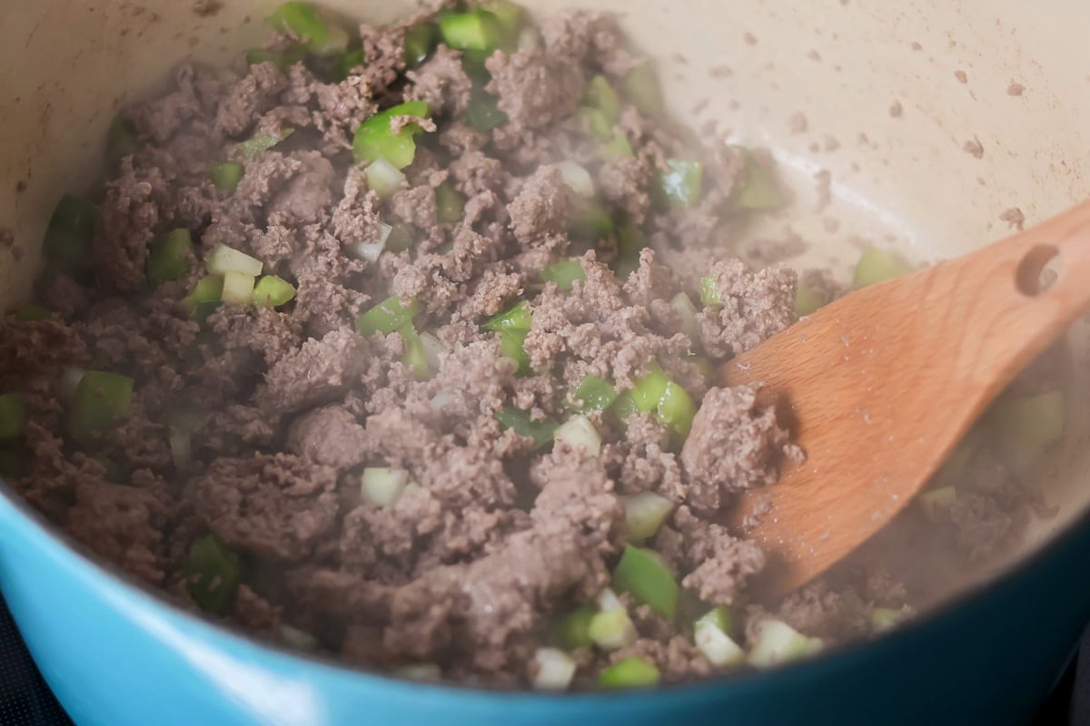 Cooking up meat and veggies in large pot.