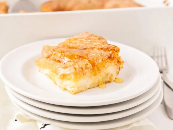 Sopapilla cheesecake slice on stack of white plates.