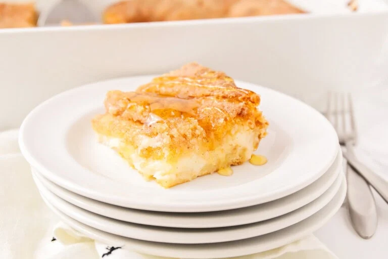 Sopapilla cheesecake slice on stack of white plates.