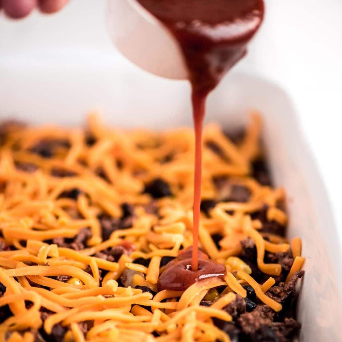 A simple twist on a favorite, our layered beef enchilada casserole is prepped in 15 minutes for a comforting classic, perfect for weeknights! Layering meat mixture in a baking dish.