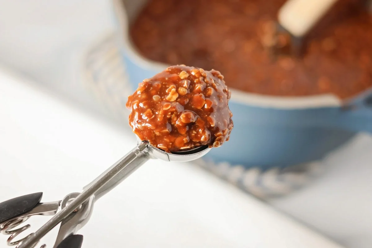 Scooping out no bake cookie mixture with cookie scoop.