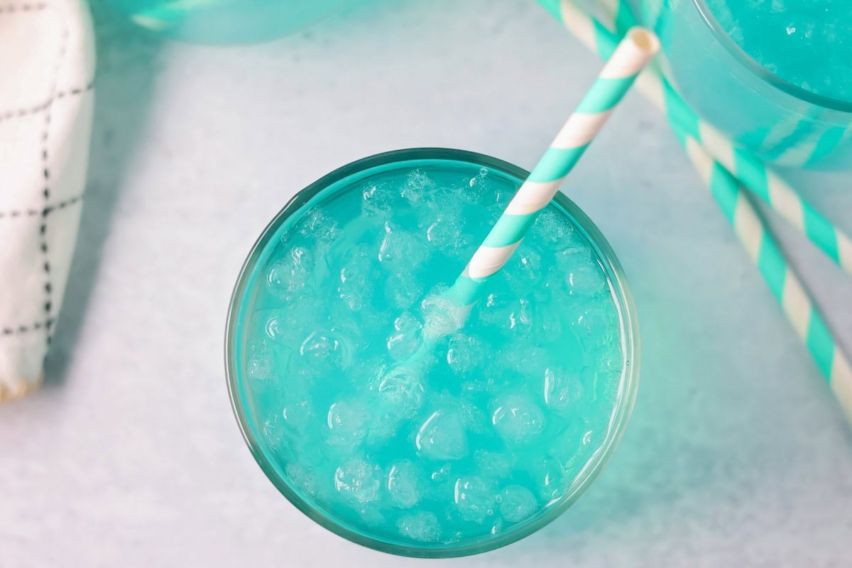 Blue punch overhead shot with ice and straw in cup.