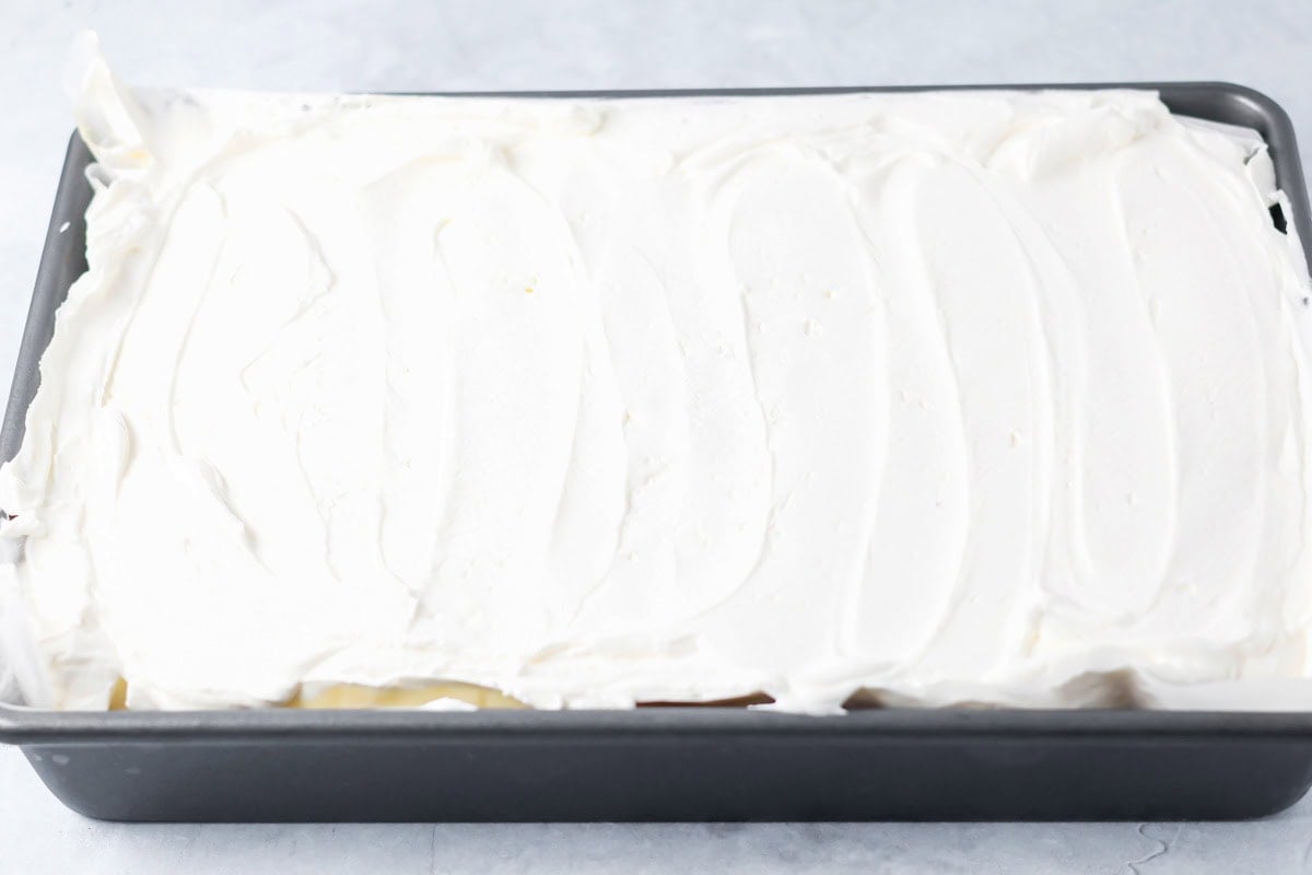 Whipped topping spread over coconut cream pie bars.
