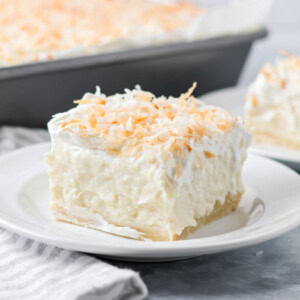 A slice of coconut cream pie bars on a white plate.