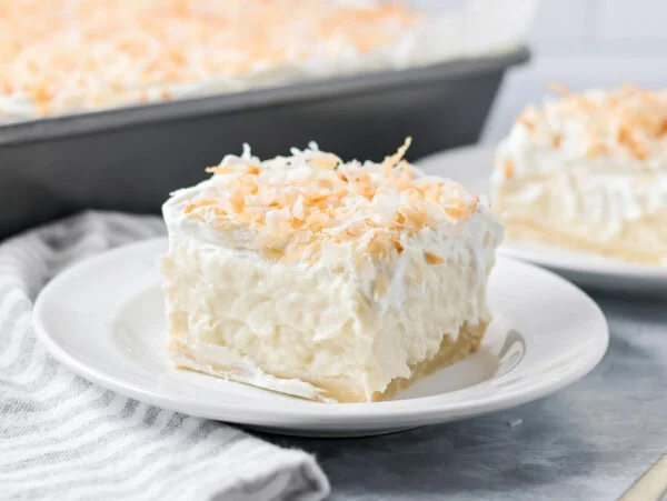 A slice of coconut cream pie bars on a white plate.