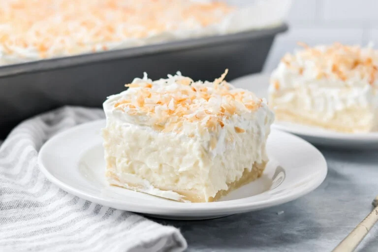 A slice of coconut cream pie bars on a white plate.