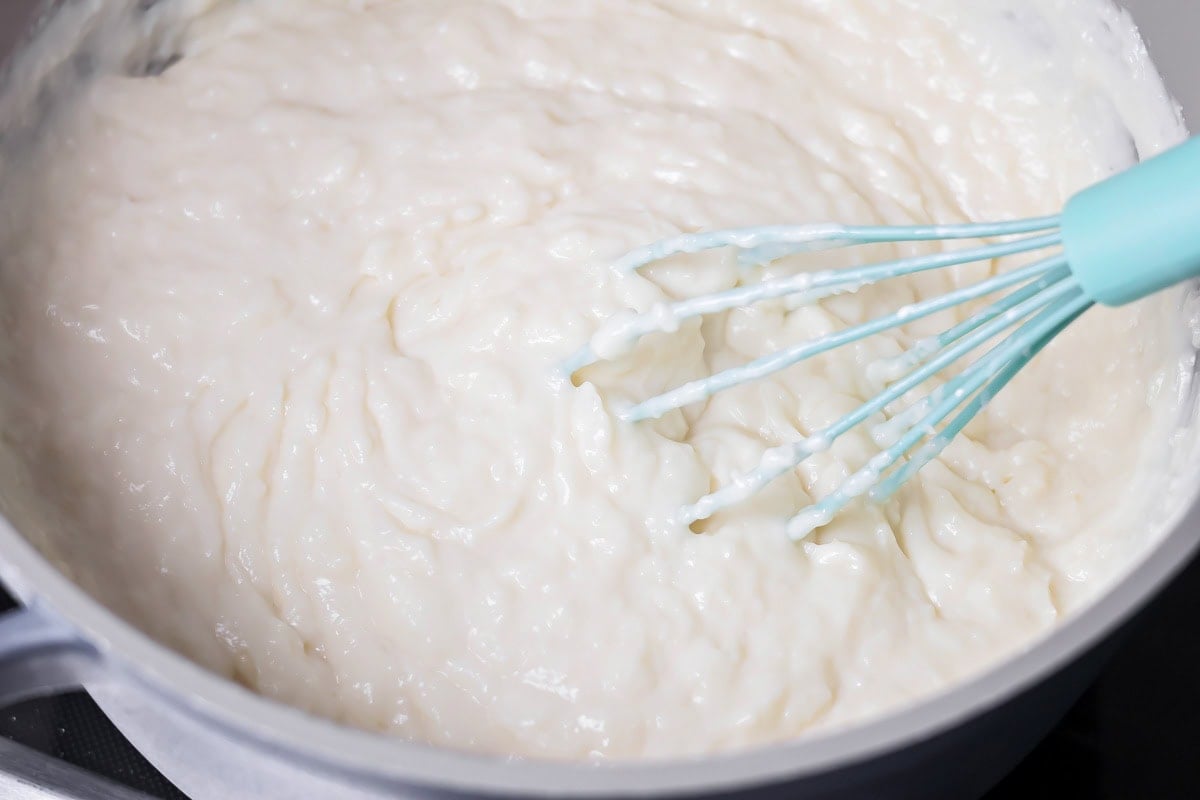 Whisking coconut cream pie filling in a pot.