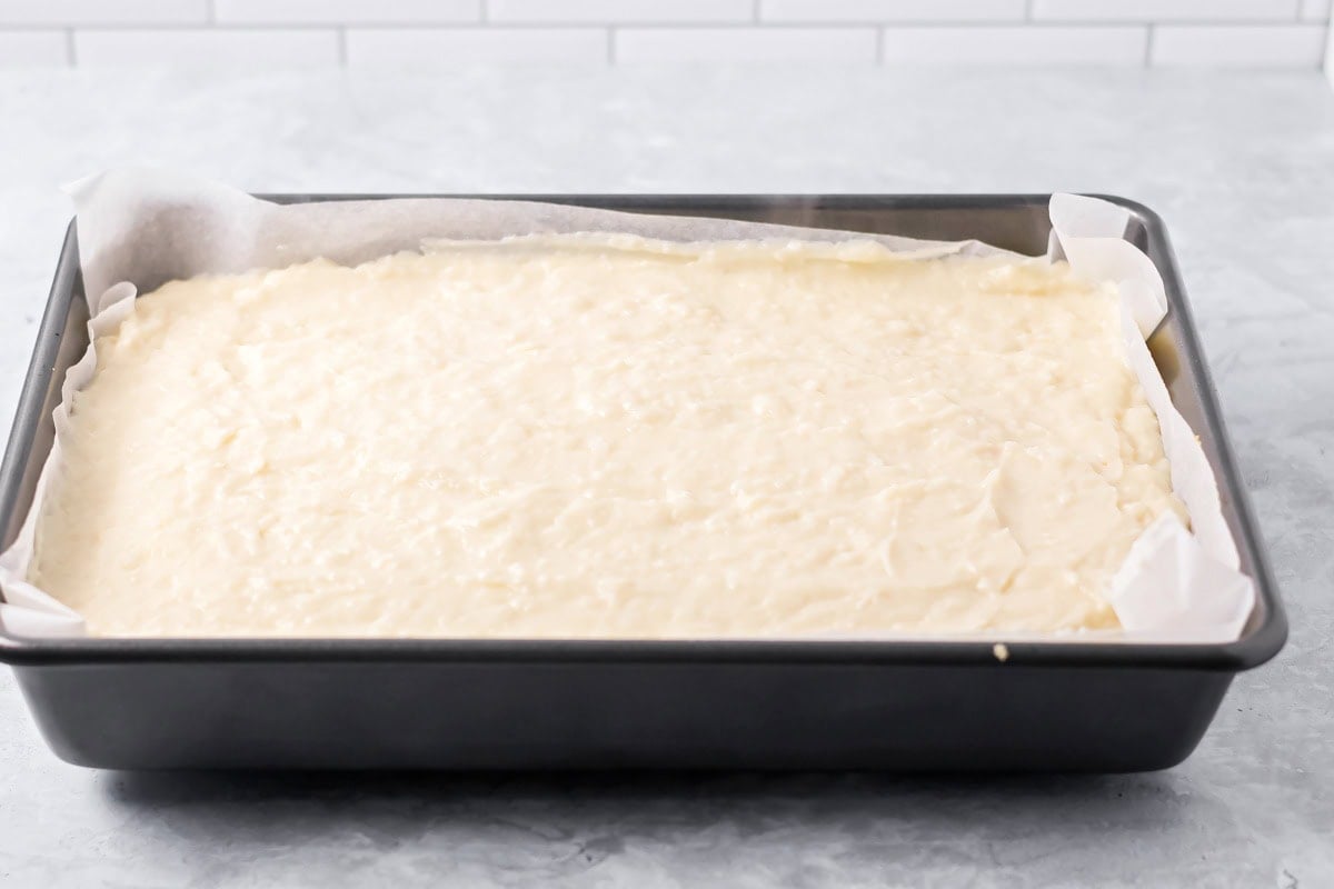 Coconut filling spread in lined baking dish.