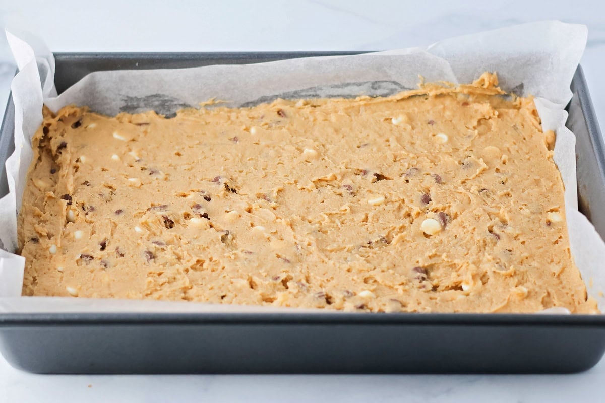 Cookie dough pressed in the bottom of a baking pan.