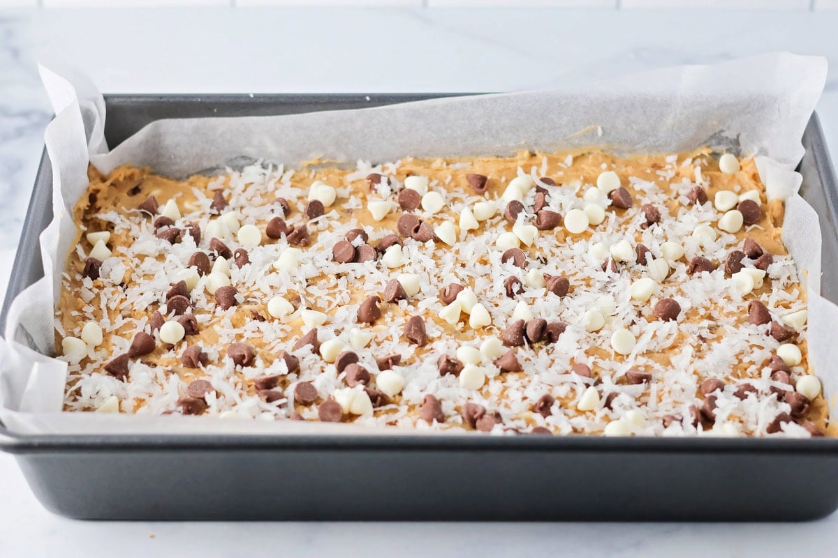 Adding coconut and baking chips to the top of congo bars.