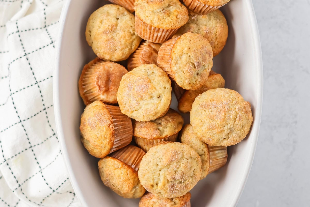 Mini Banana Muffins in bowl with dishcloth on the side.